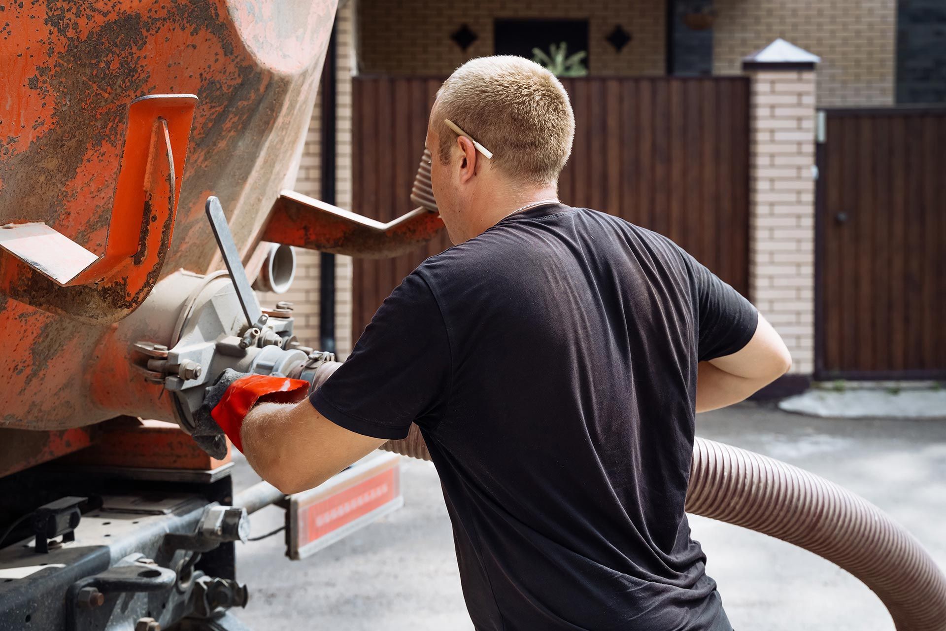 Worker connecting a hose to a large tanker truck during service.