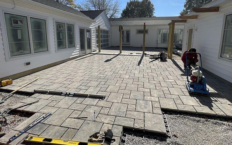 A patio is being built in front of a white house.