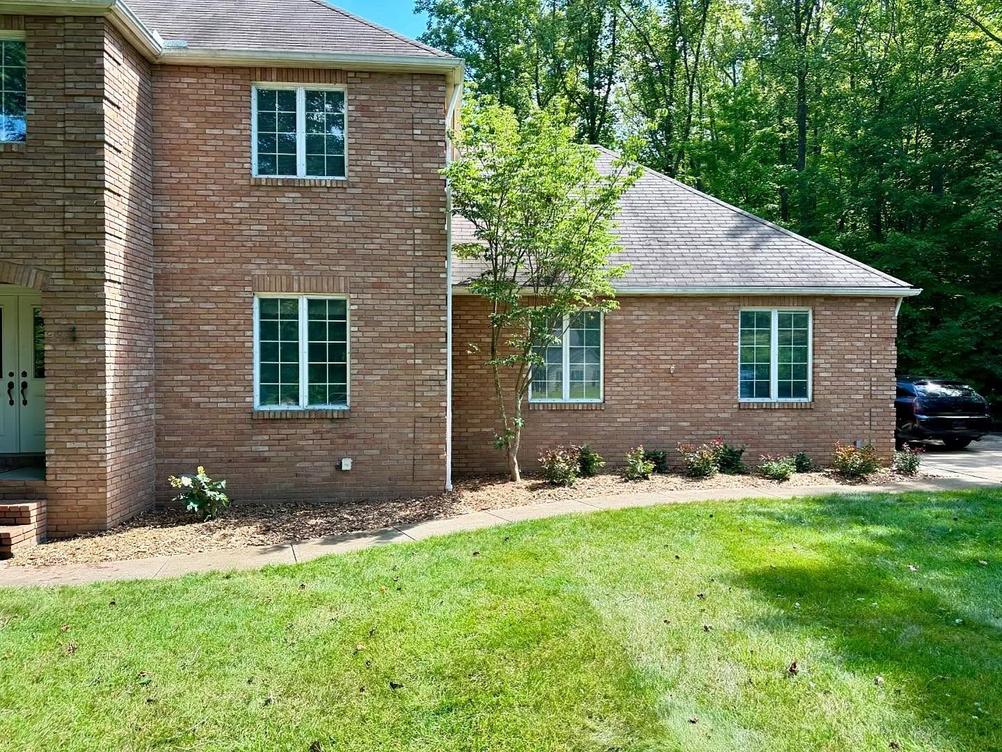 A large brick house with a lush green lawn in front of it.