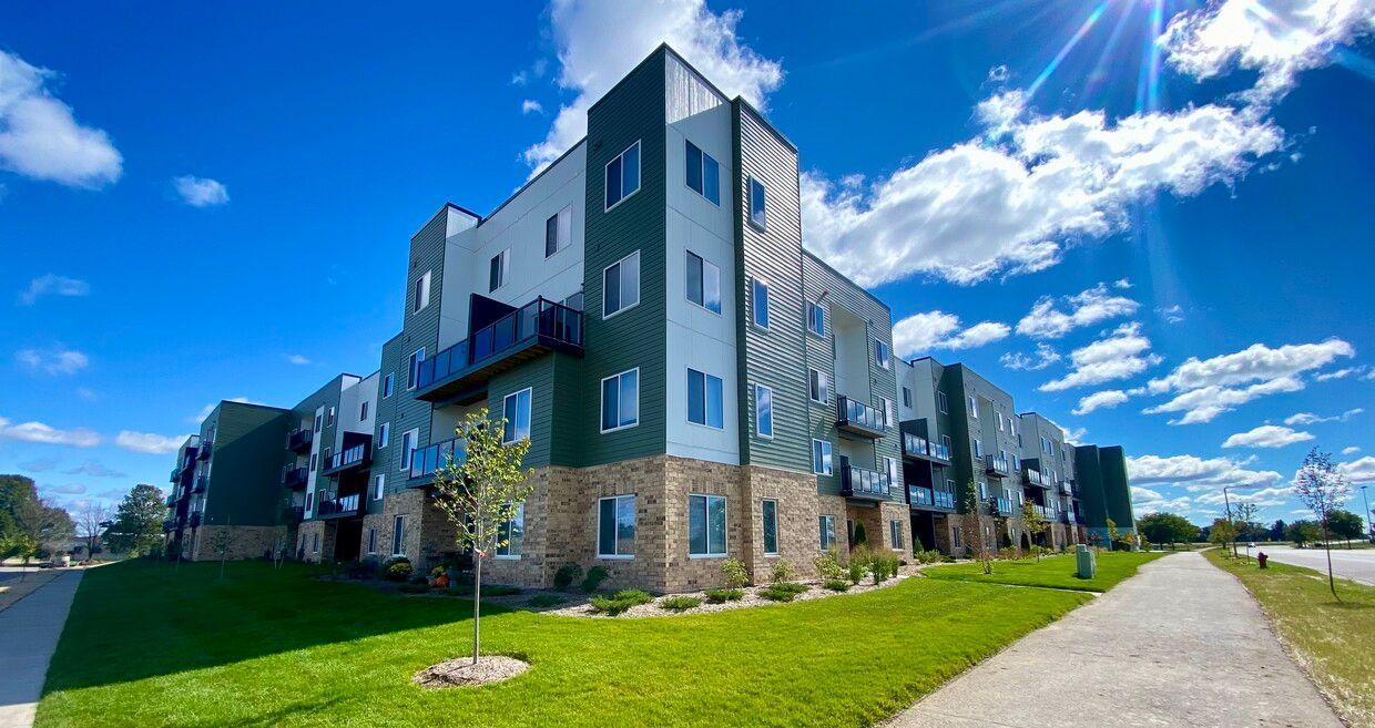 A large apartment building with a path leading to it on a sunny day.
