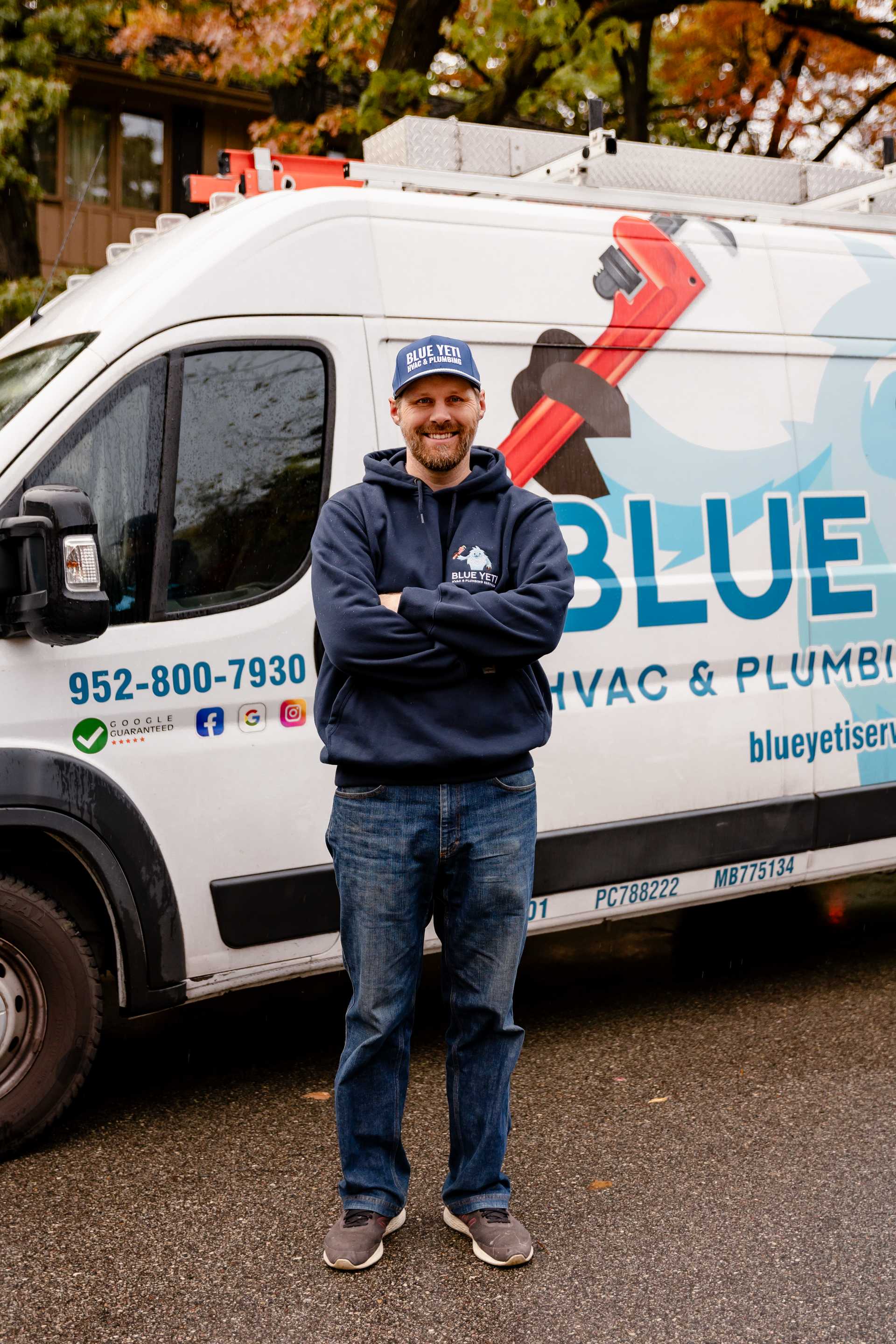 Technician in front of a Blue HVAC & Plumbing service van