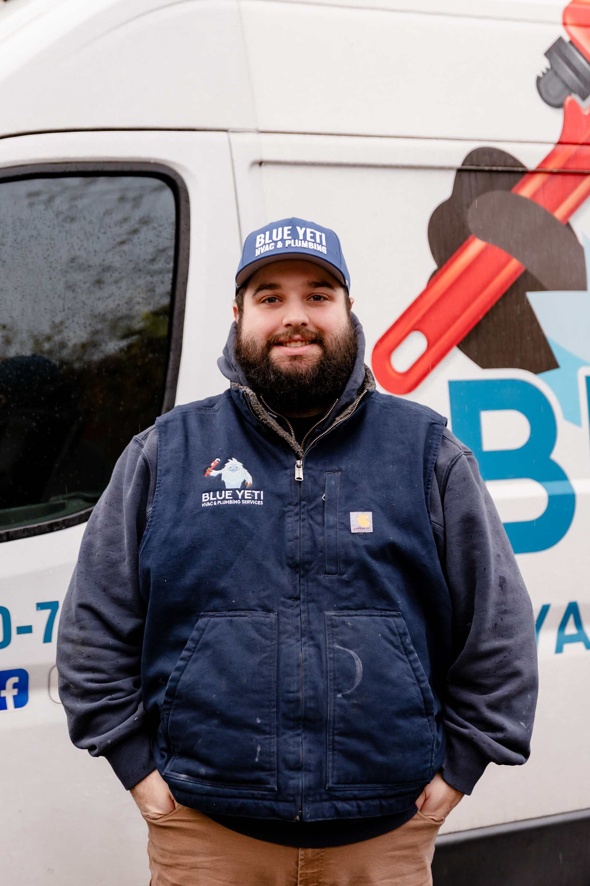 Blue HVAC & Plumbing team member standing outside service van