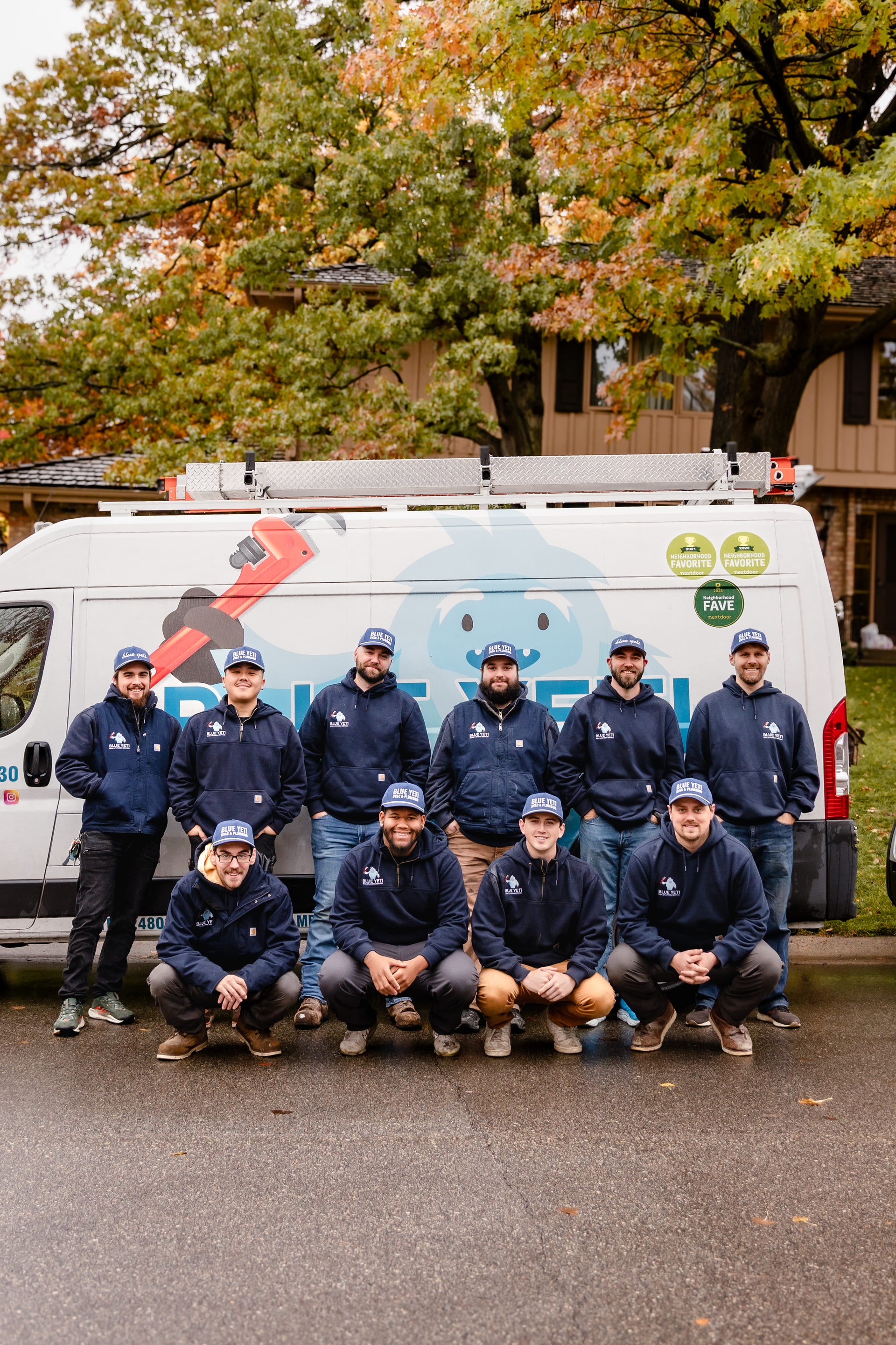 Group of Blue Yeti HVAC Plumbing HVAC technicians in navy blue sweatshirts posing in front of a company van