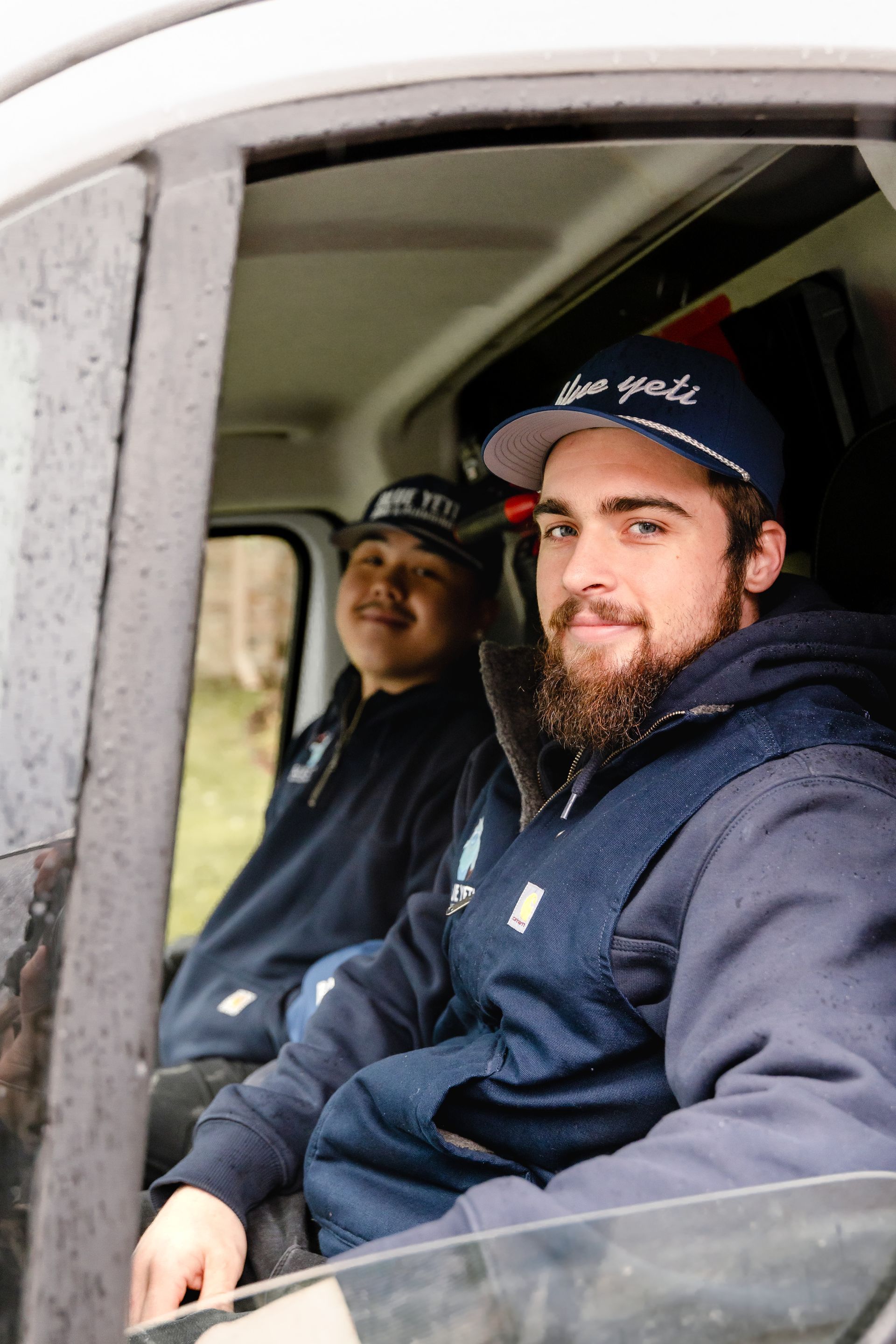 Two Blue Yeti HVAC Plumbing technicians sitting in company van reparing for maintenance