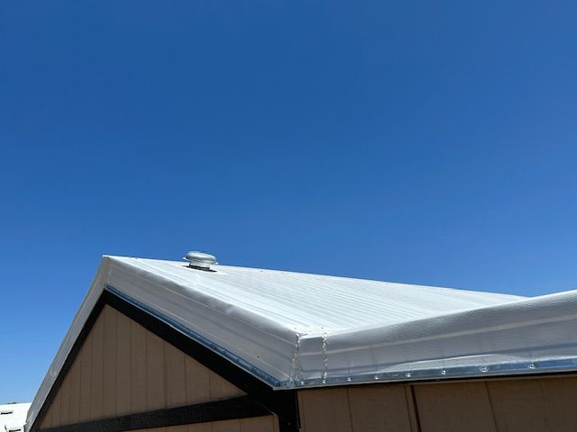 Metal roof on a light brown building against a clear blue sky.