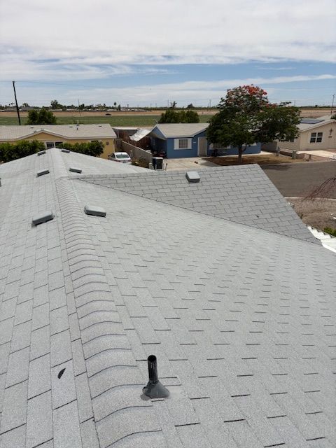 Gray shingled roof with multiple vents, overlooking a neighborhood on a sunny day.