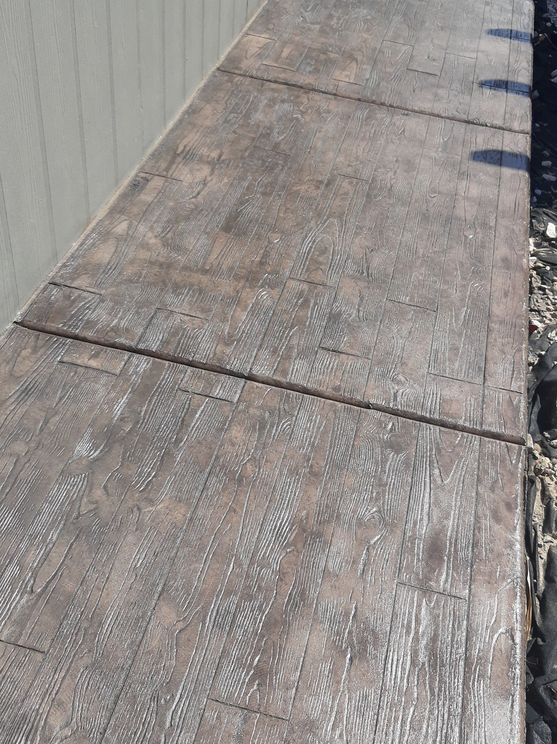 Brown stamped concrete walkway with a wood grain pattern.