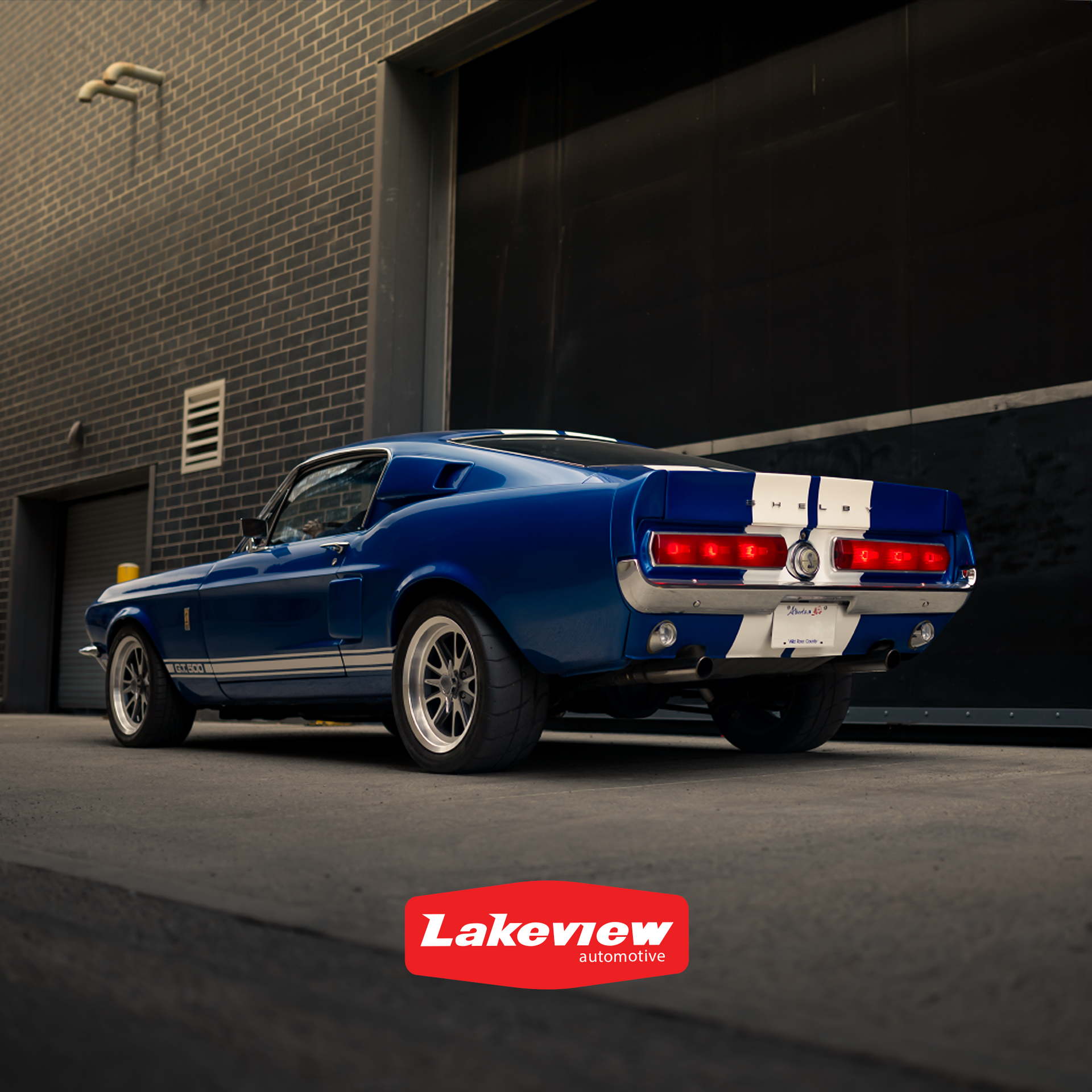a blue 67 mustang is parked in front of a brick building