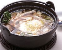 Un pot de soupe avec des nouilles et des légumes sur une table.