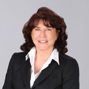 A woman wearing a black jacket and white shirt smiles for the camera