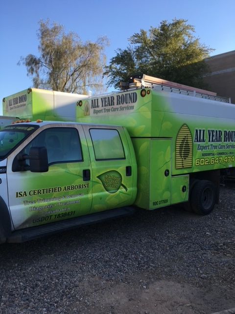 Green and white All Year Round service truck parked outside.