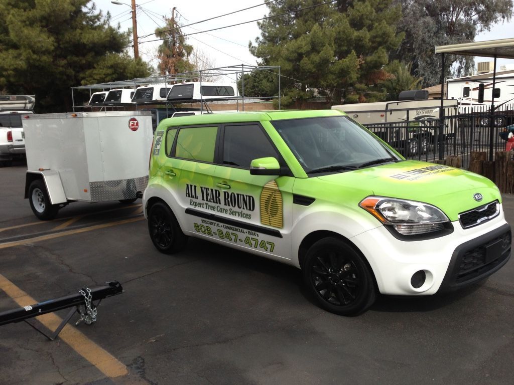 Green and white Kia Soul towing a white trailer, parked outdoors.