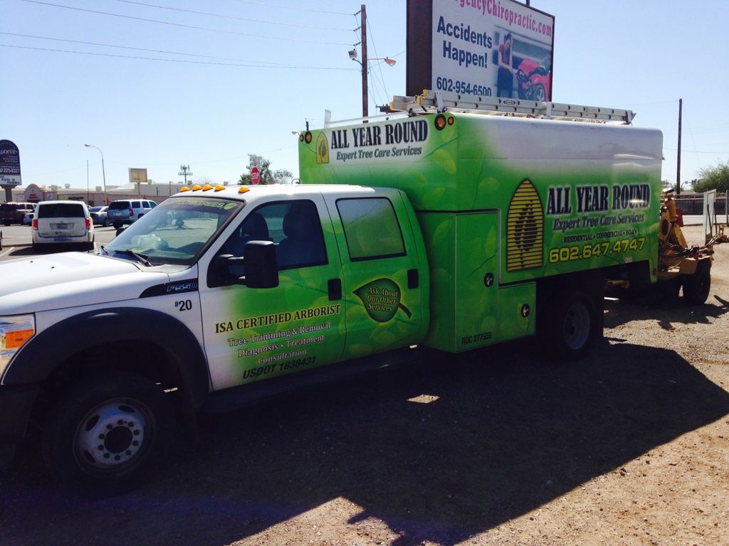 White truck with green wrap for All Year Pest Control parked outside.