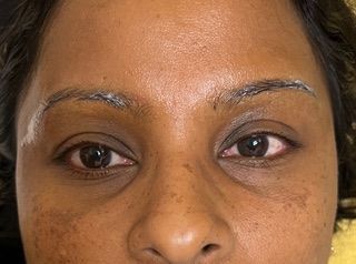 A close up of a woman 's face with makeup on her eyebrows.