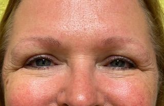 A close up of a woman 's face with blue eyes and red cheeks.