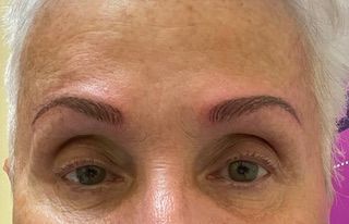 A close up of a woman 's face with gray hair and green eyes.