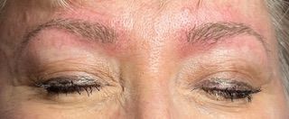 A close up of a woman 's face with a red spot on her forehead.