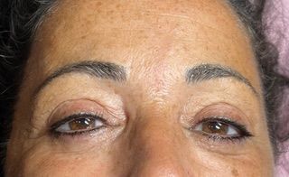 A close up of a woman 's face with brown eyes and freckles.