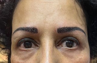 A close up of a woman 's face with a tattoo on her eyebrows.