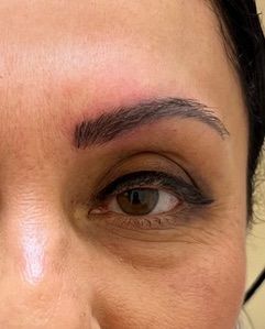 A close up of a woman 's face with a tattoo on her eyebrow.