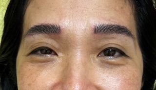 A close up of a woman 's face with a tattoo on her eyebrows.