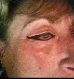 A close up of a woman 's face with eyeliner on her eye.