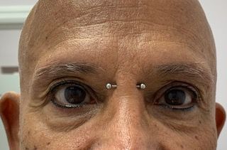 A close up of a man 's face with a nose ring.