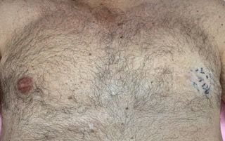 A close up of a man 's chest with a tattoo on it.