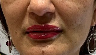 A close up of a woman 's face with red lips and earrings.