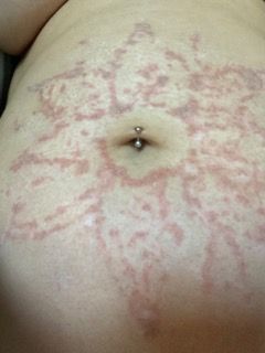 A close up of a woman 's stomach with a belly button piercing.