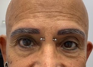 A close up of a man 's face with a nose ring.