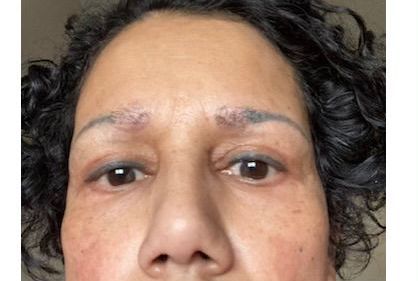 A close up of a woman 's face with a tattoo on her eyebrows.