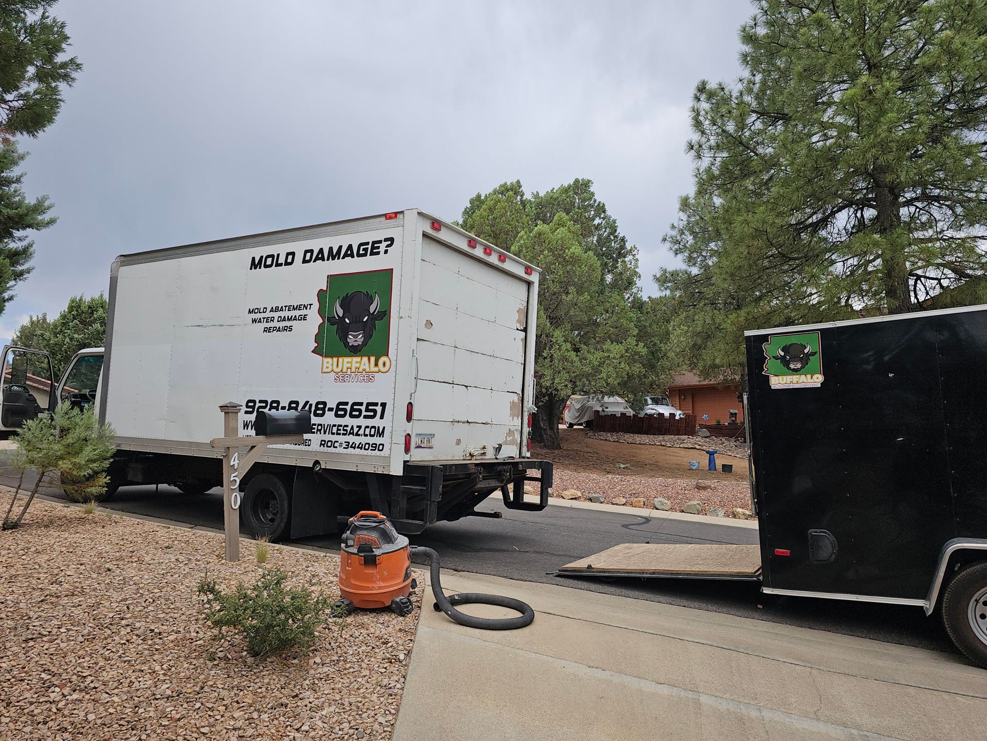 A white moving truck is parked next to a black trailer.