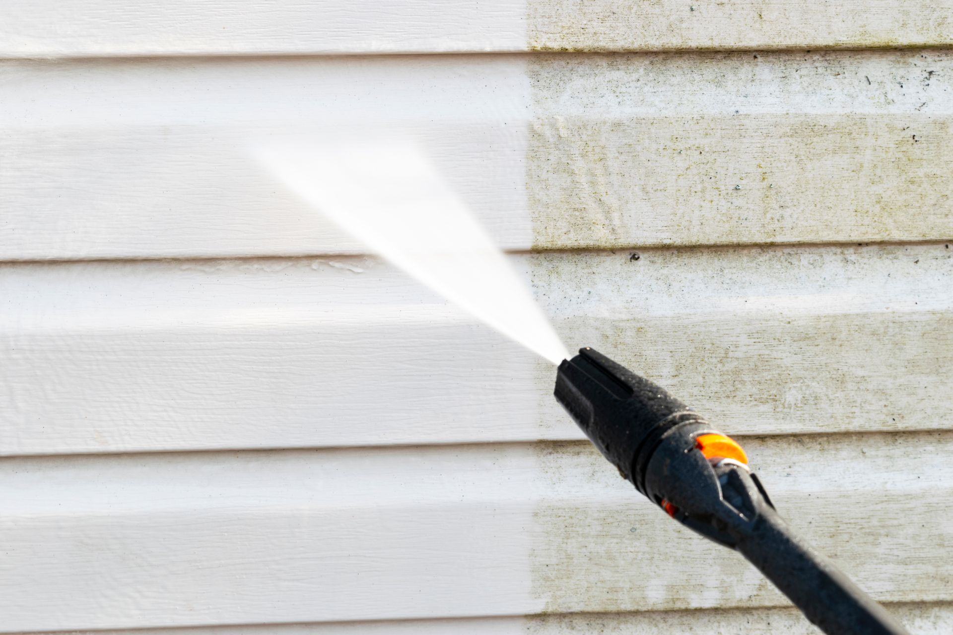 A professional using high-pressure water jets to clean the building facade.