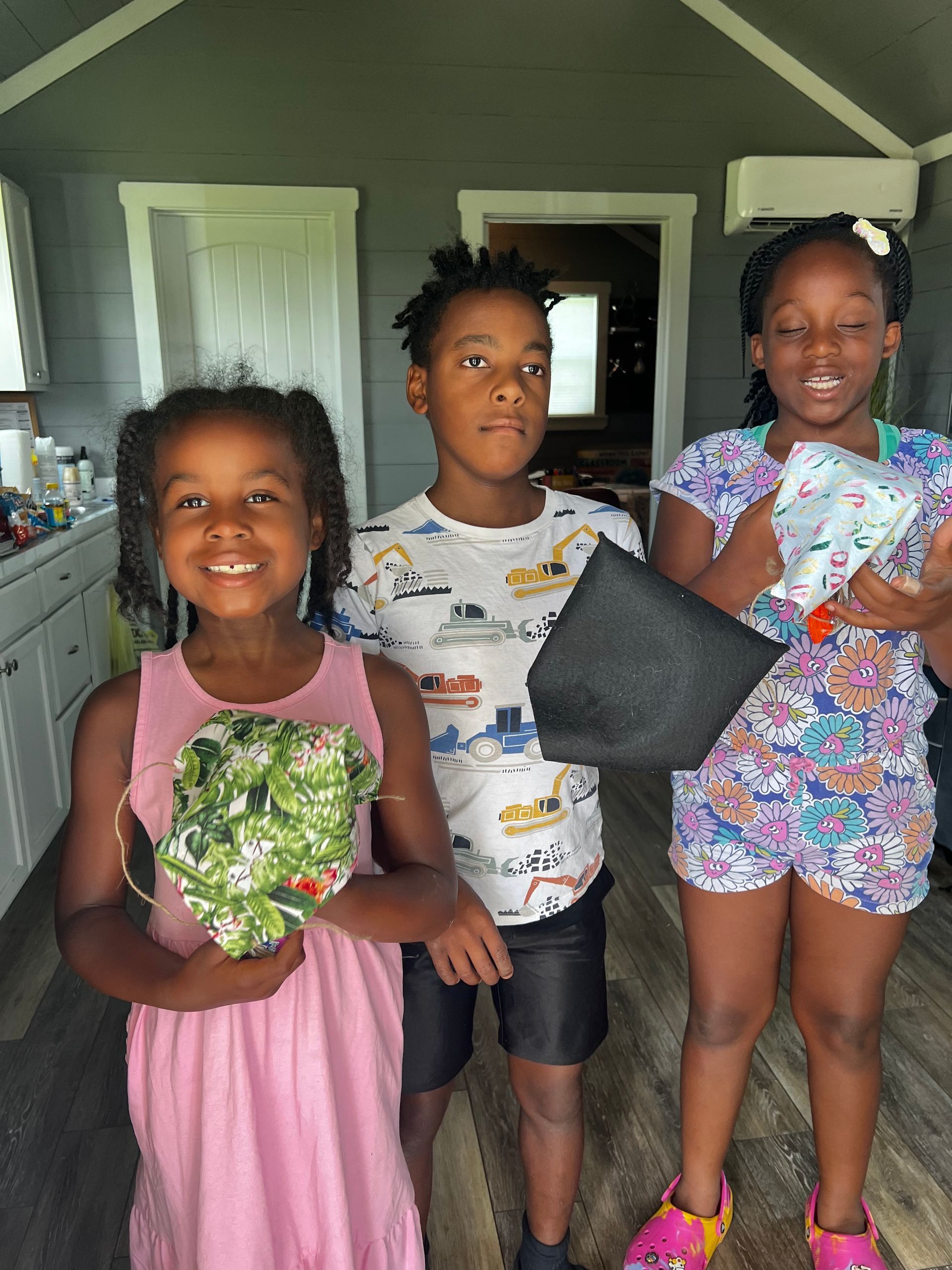 A boy and two girls are standing next to each other in a room.