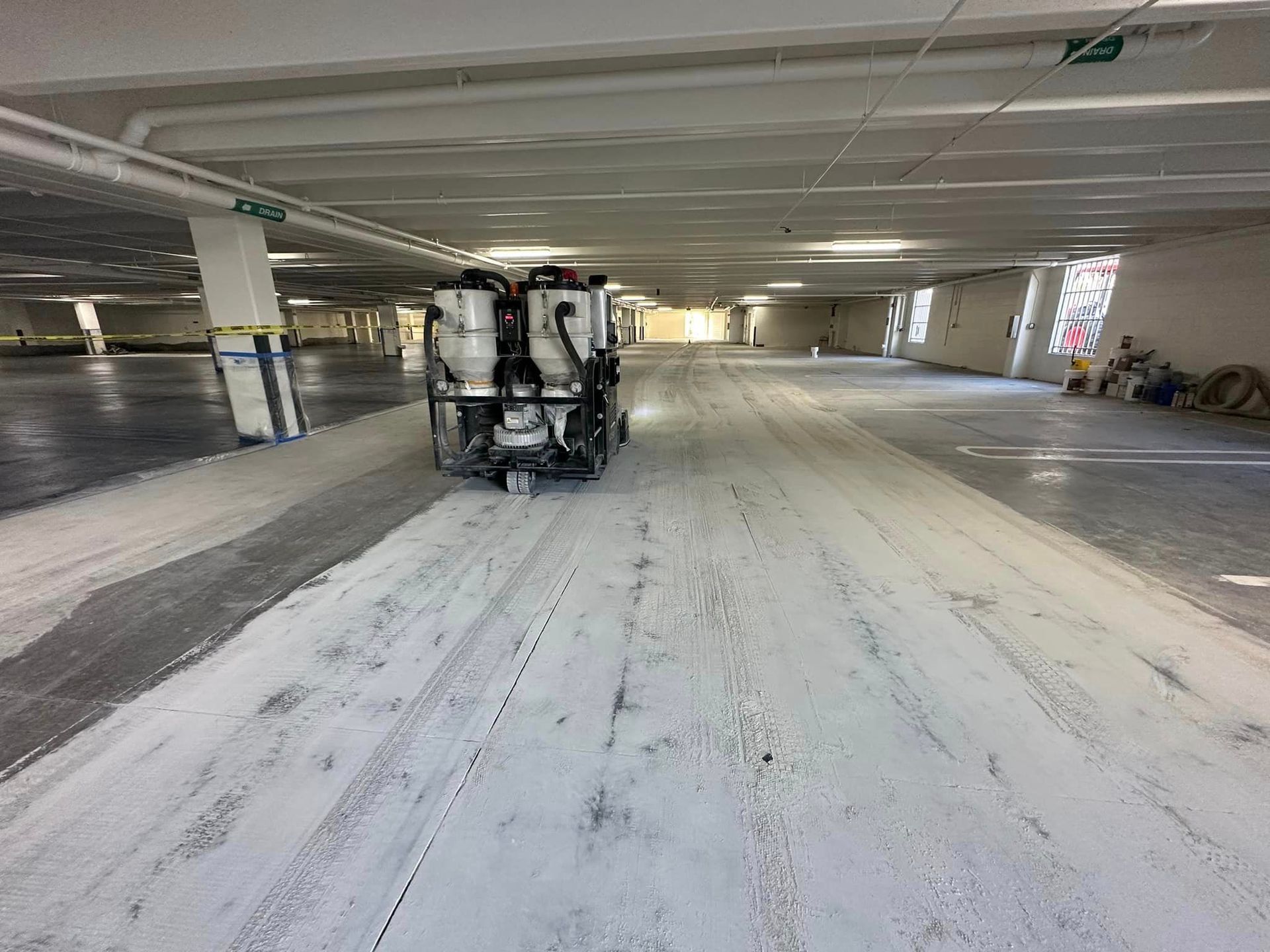 A machine is grinding the concrete in a parking garage.