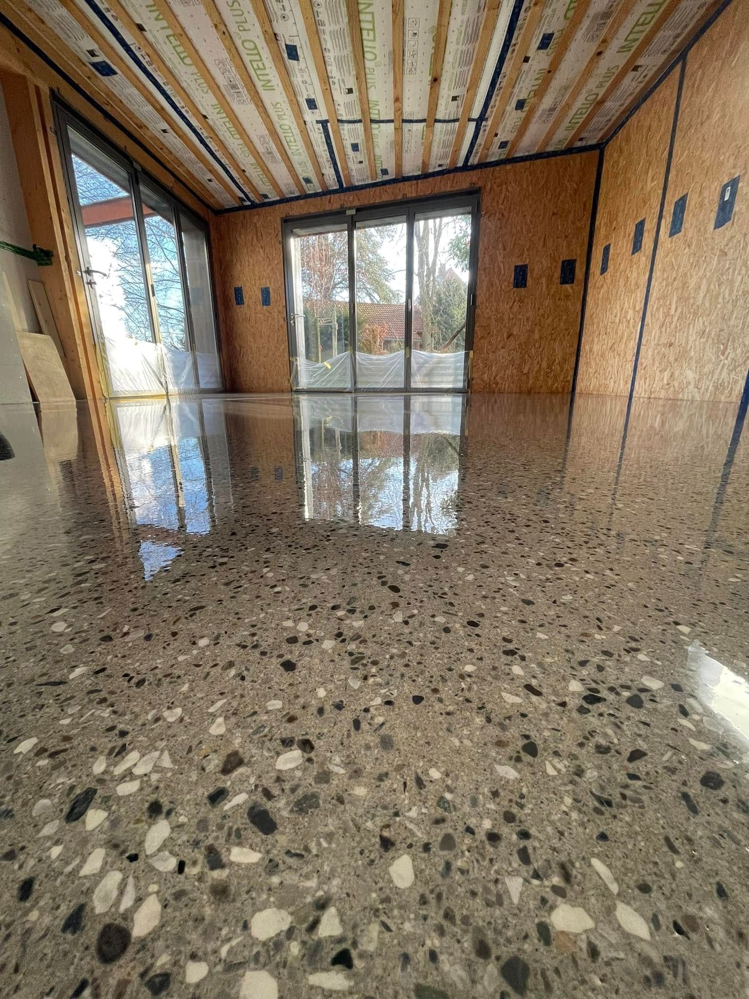 A room with a polished concrete floor and sliding glass doors.