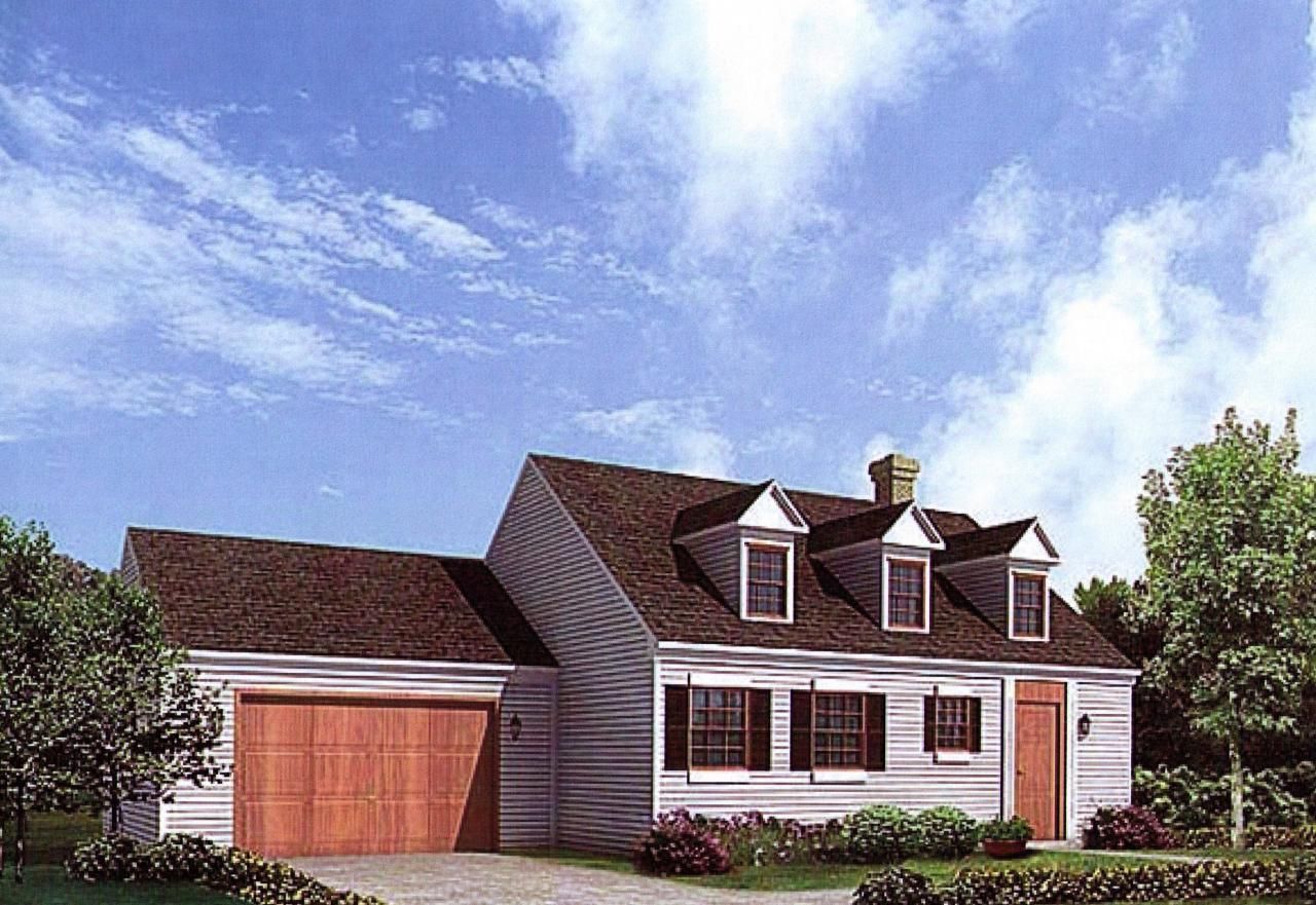 A white house with a brown roof and a wooden garage door