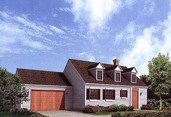 A white house with a brown roof and a wooden garage door