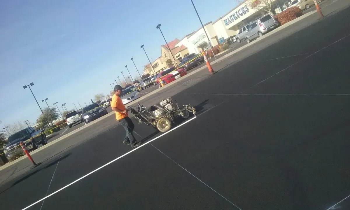 A Man is Painting White Line on the Parking Lot — Prescott, AZ — Maurer Sealing & Striping