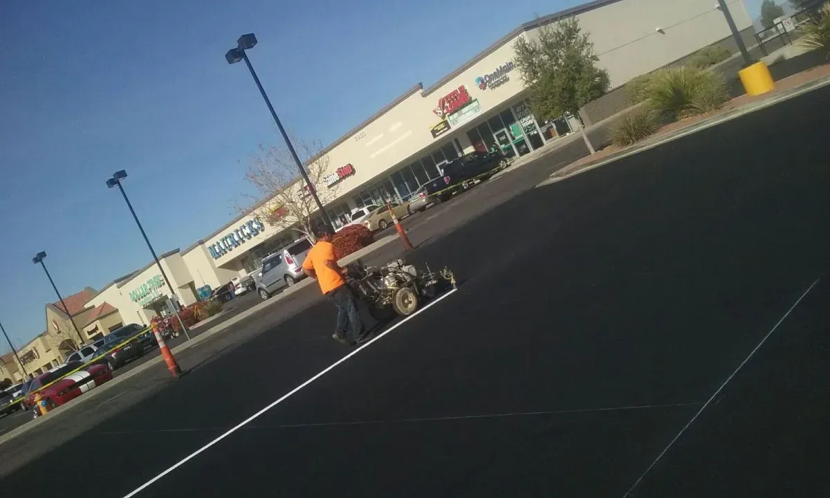 A Man Painting White Line in an Empty Parking Lot — Prescott, AZ — Maurer Sealing & Striping