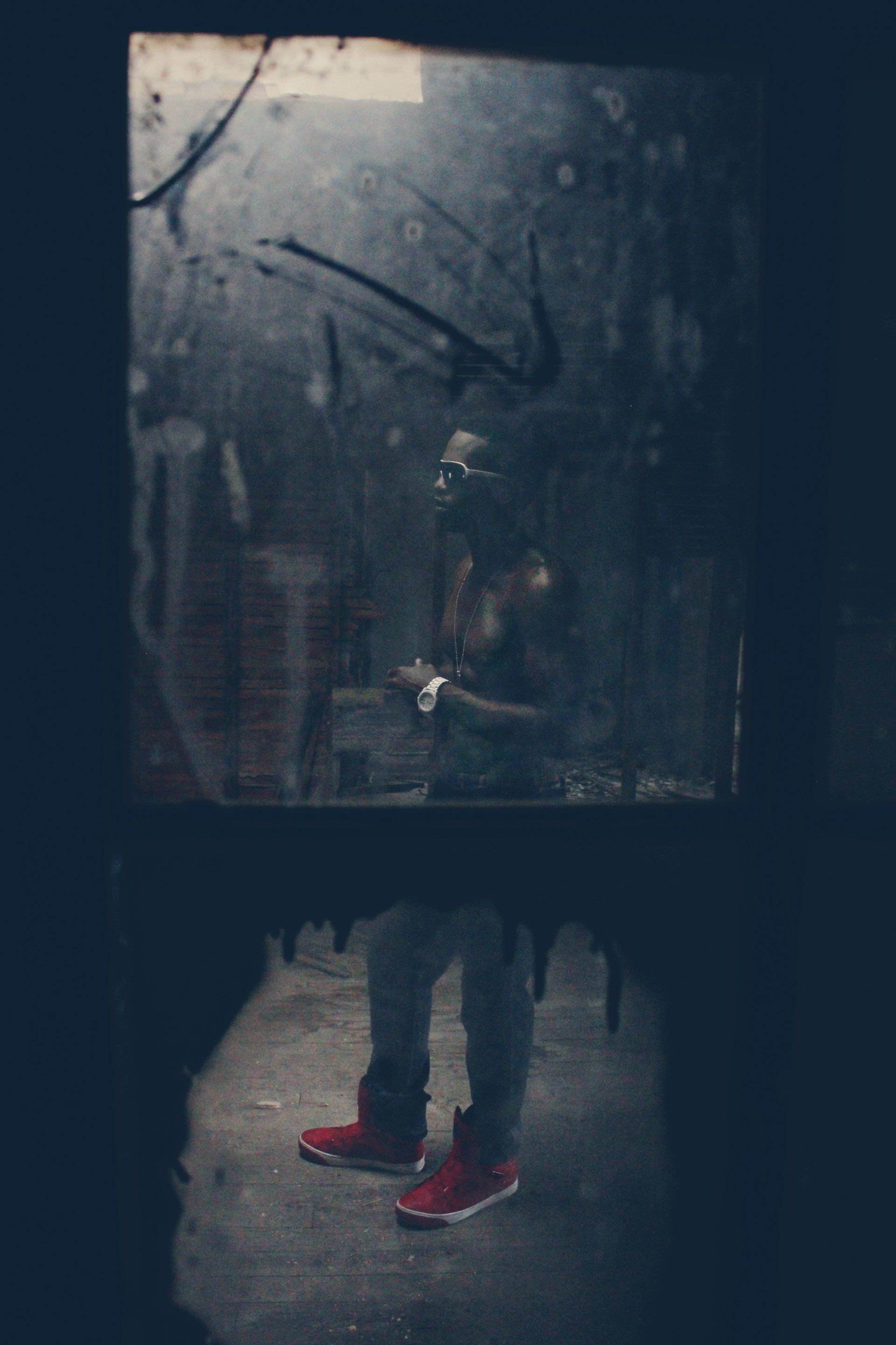 MLN standing in front of a window in a dark room.