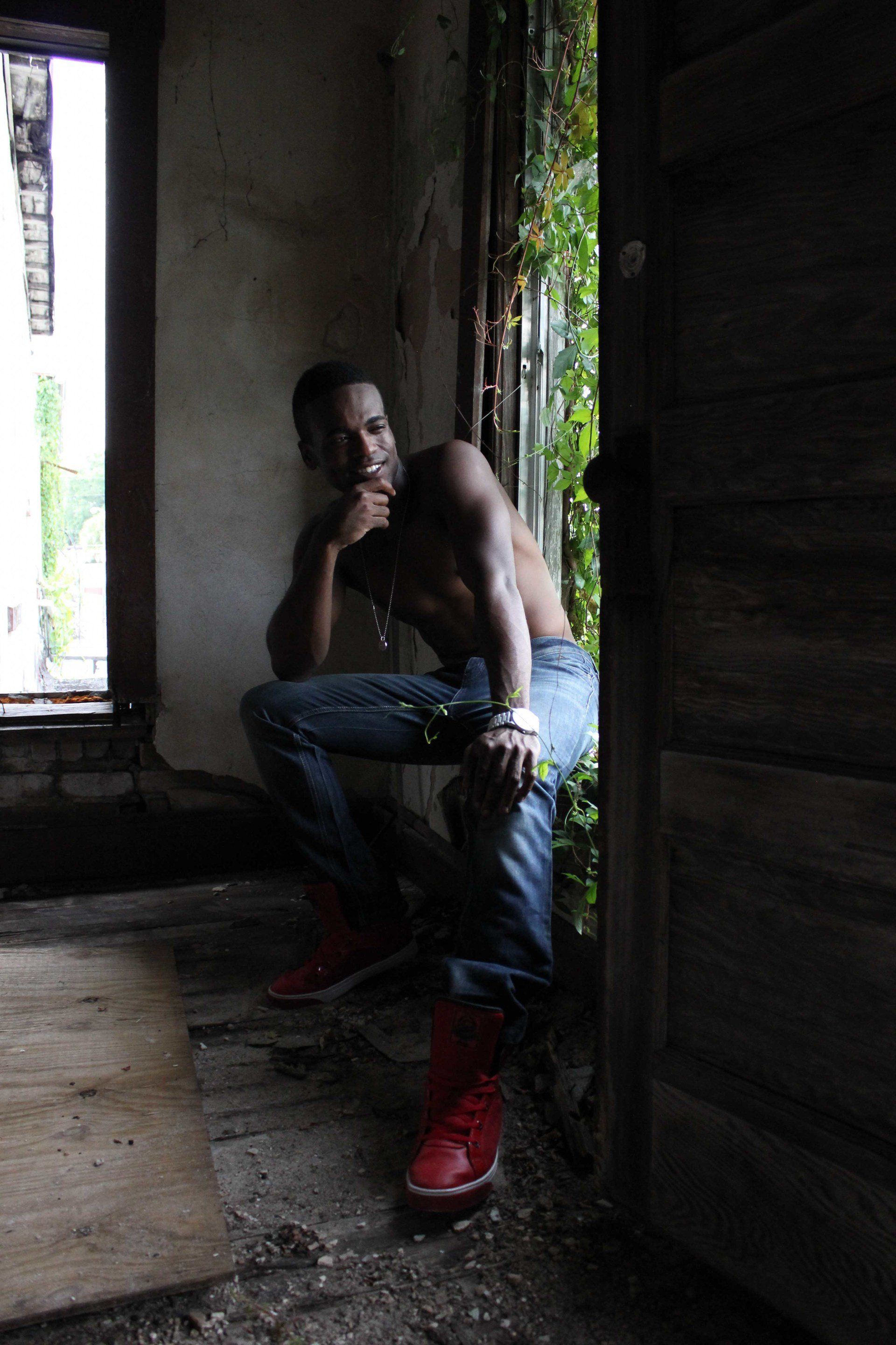 MLN is sitting in a dark room next to a door.