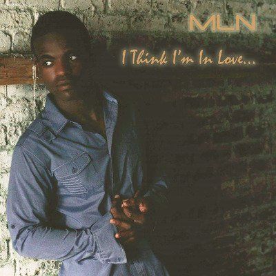 MLN standing in front of a brick wall with the words i think i 'm in love