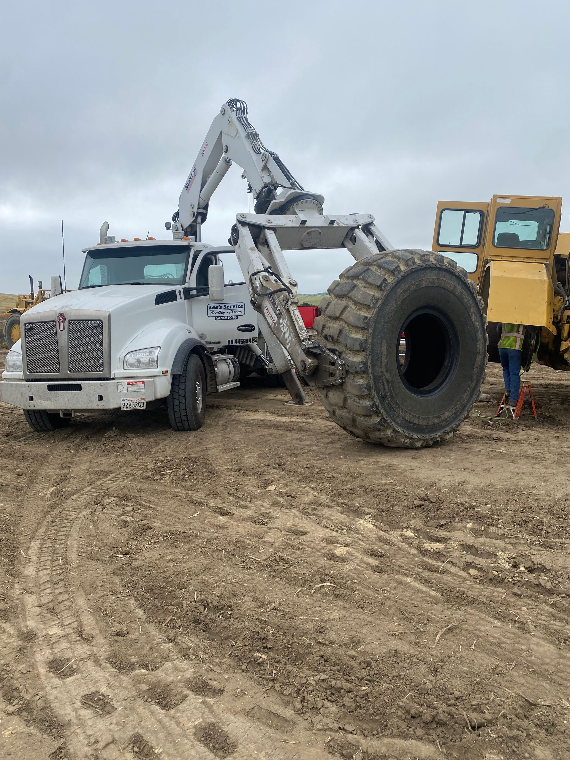 a large off road tire is being loaded onto a truck in a dirt field