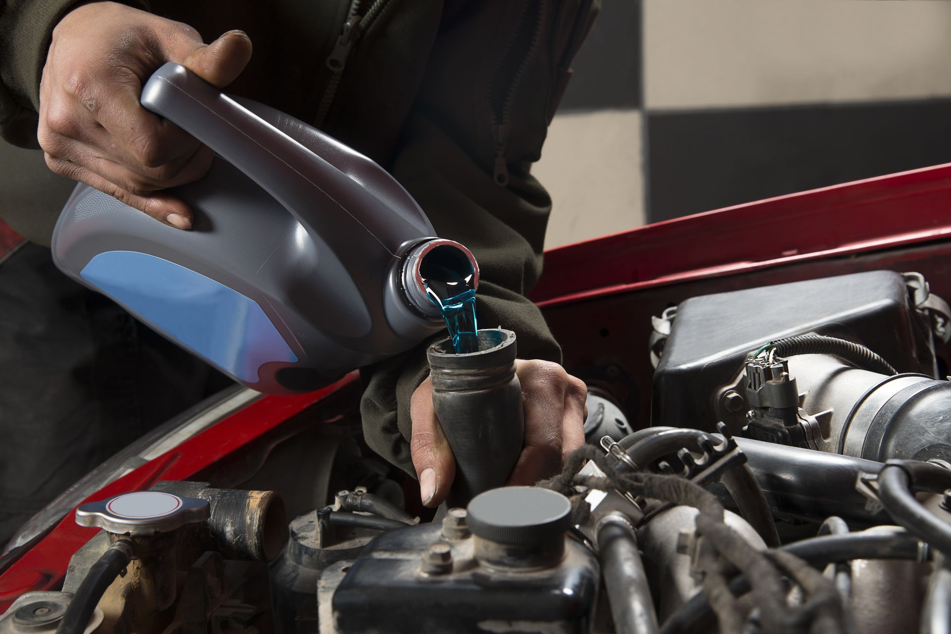 A man is pouring oil into a car engine.