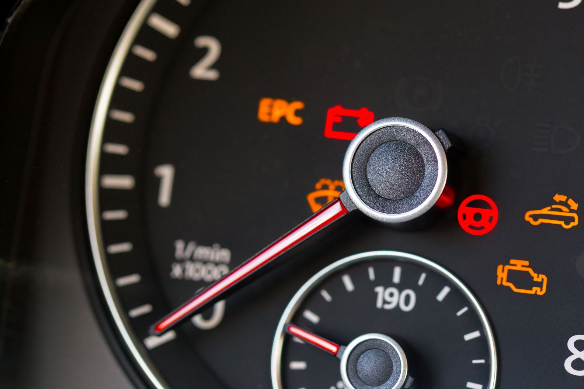 Close-up car dashboard with speedometer needle and illuminated warning lights, including EPC and engine icons
