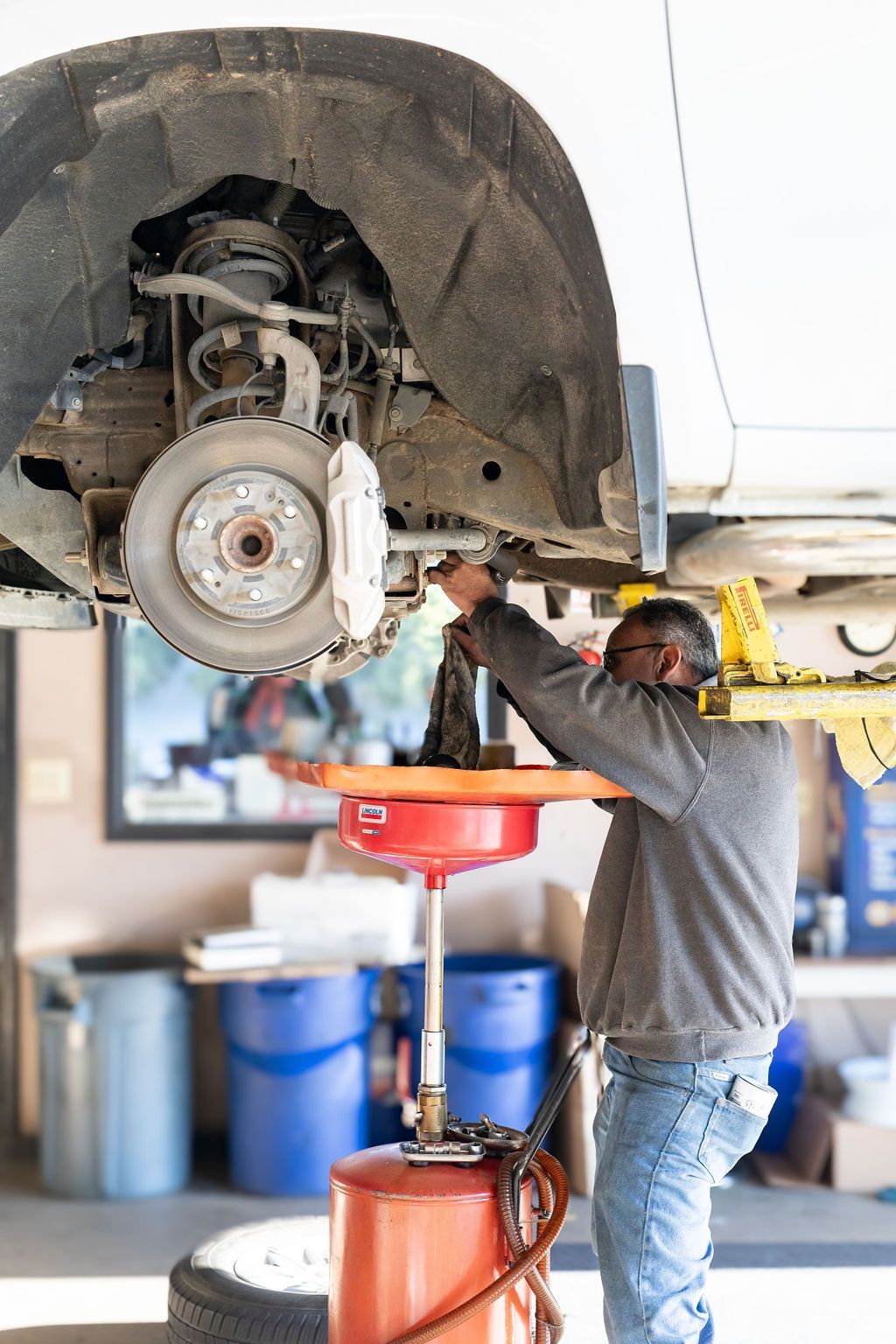 A man is working on the underside of a car in a garage
