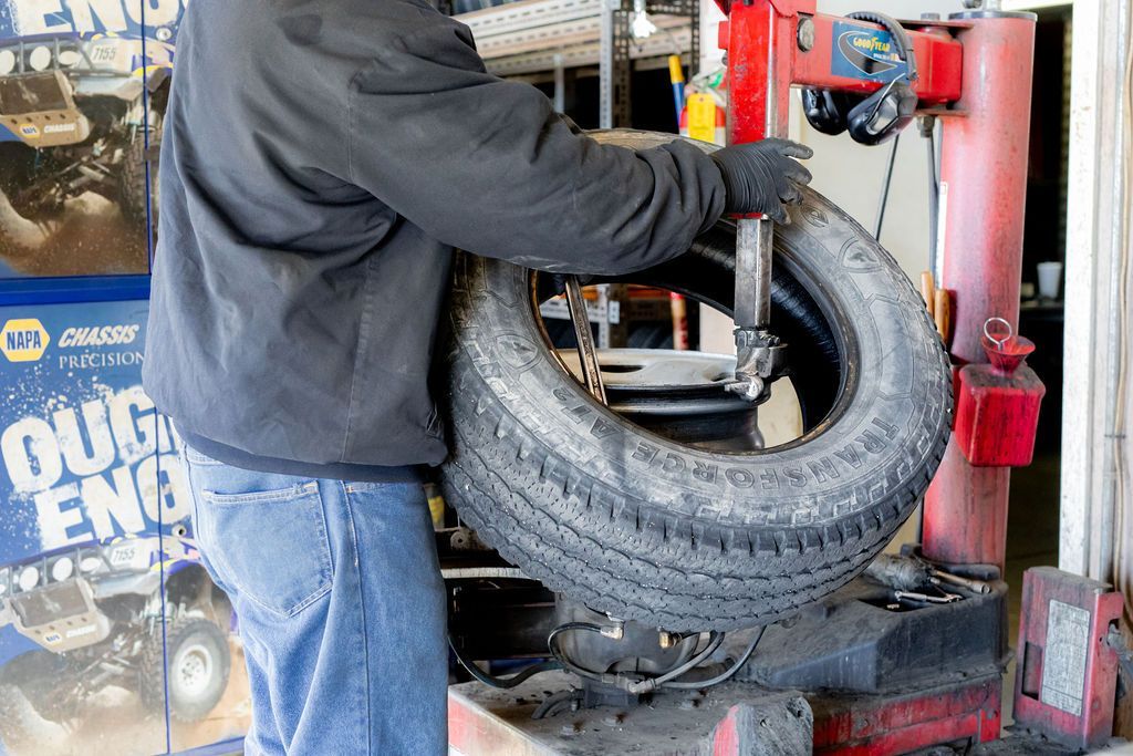 A man is working on a tire in front of a sign that says quick end