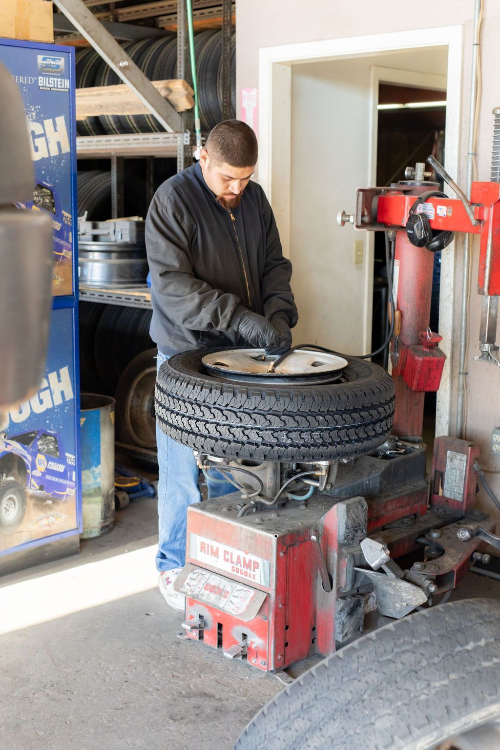 A man is working on a tire on a machine that says ' bfgoodrich ' on it